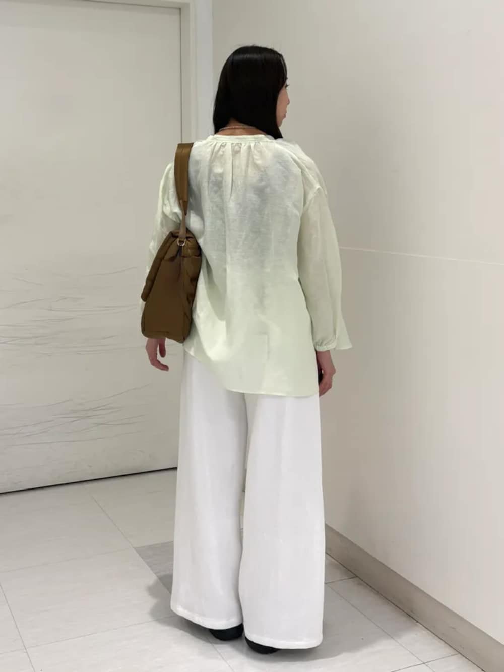 ホワイト系のデニムパンツ、ブラック系のスニーカー、イエロー系のショルダーバッグを着用したレディースの春コーディネートの3枚目の写真