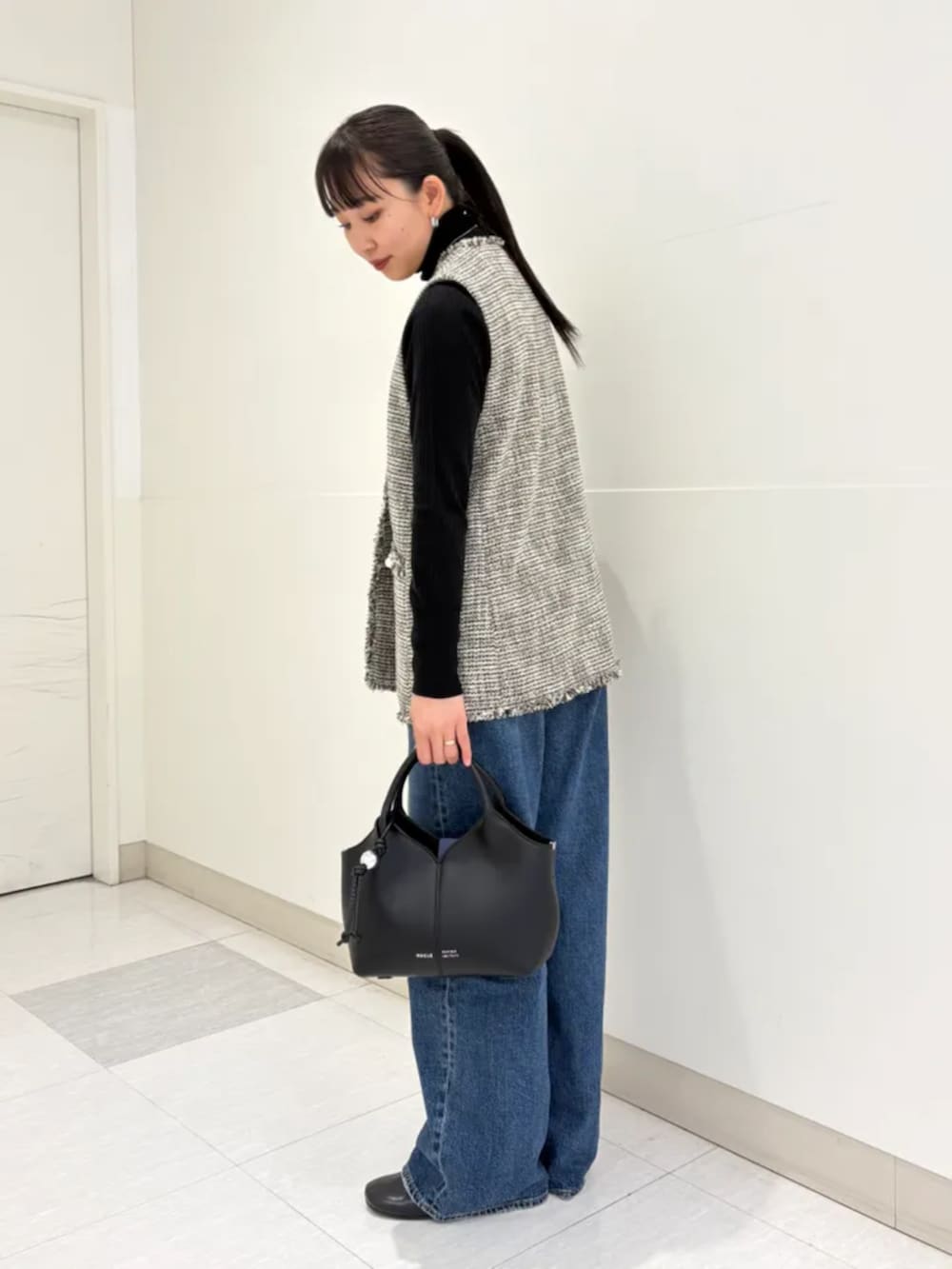 ブラック系のショルダーバッグ、ブルー系のデニムパンツ、ブラック系のニット/セーターを着用したレディースの冬コーディネートの2枚目の写真
