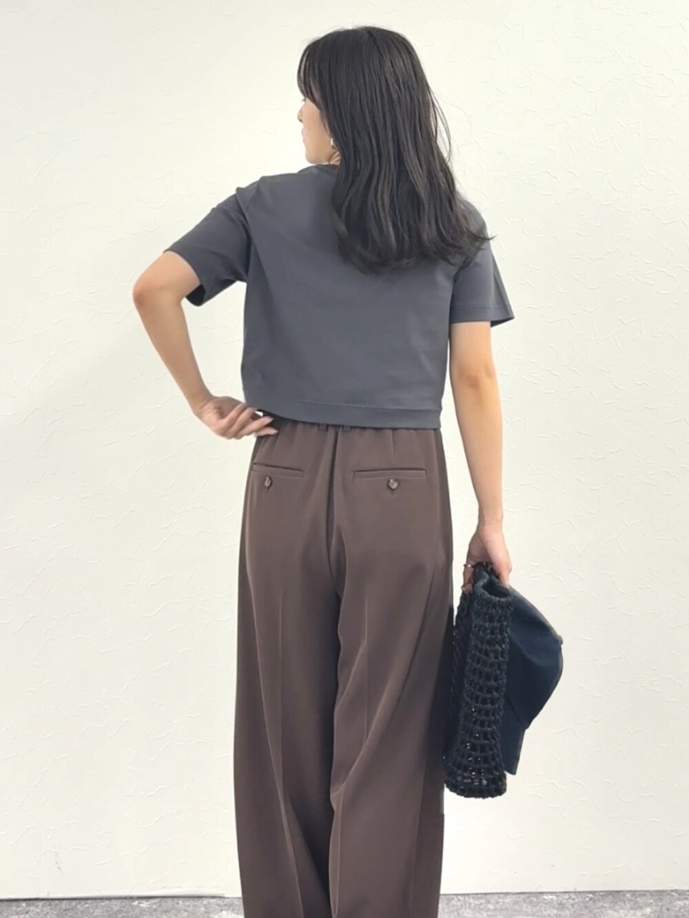 グレー系のTシャツ/カットソー、ブラウン系のその他パンツ、ブラック系のかごバッグを着用したレディースの春コーディネートの4枚目の写真
