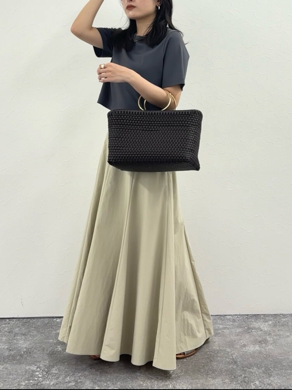 グレー系のTシャツ/カットソー、ベージュ系のスカート、ブラウン系のかごバッグを着用したレディースの春コーディネートの2枚目の写真