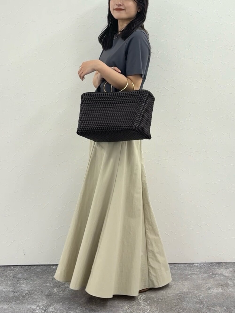 グレー系のTシャツ/カットソー、ベージュ系のスカート、ブラウン系のかごバッグを着用したレディースの春コーディネートの4枚目の写真