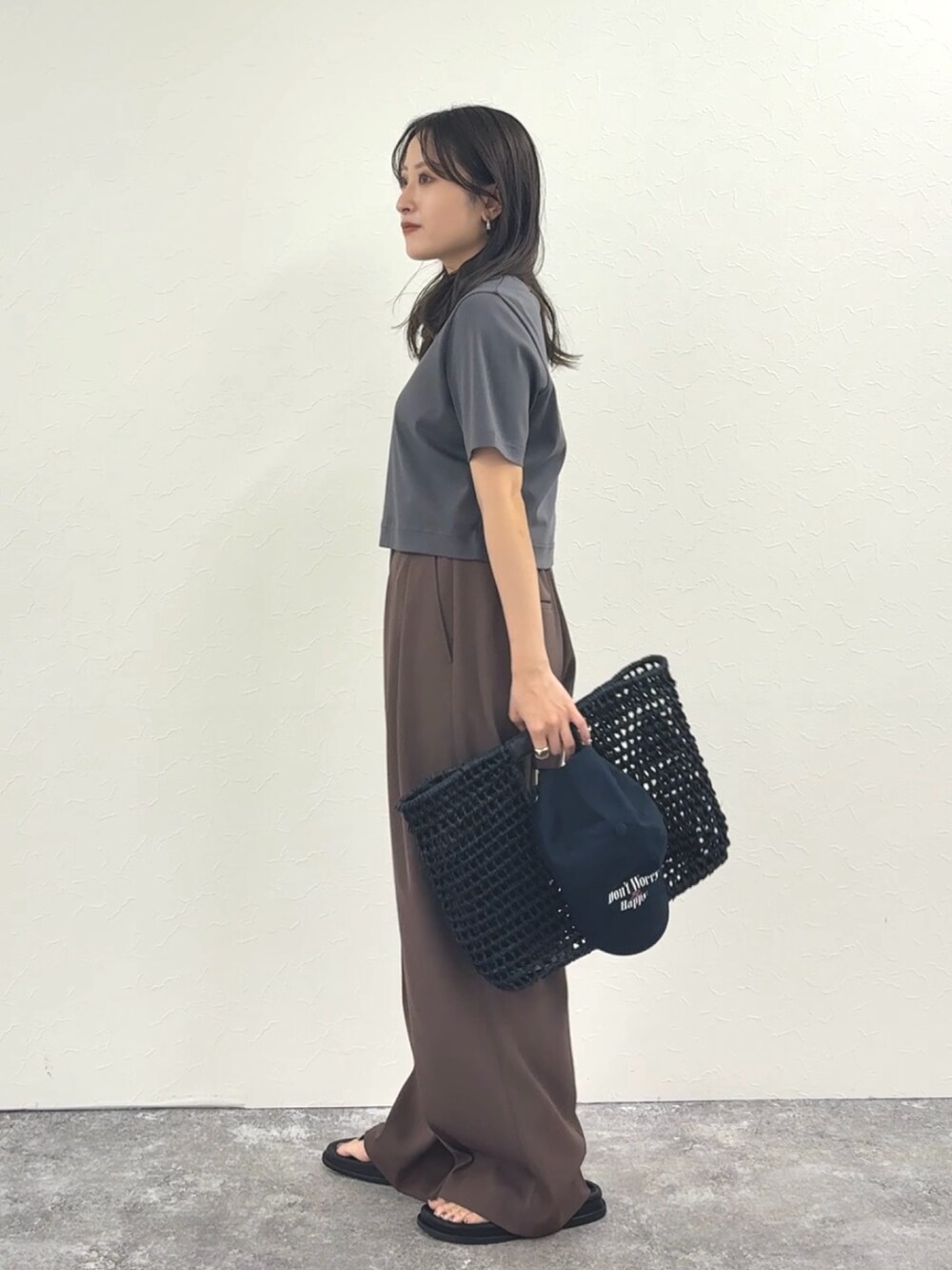 グレー系のTシャツ/カットソー、ブラウン系のその他パンツ、ブラック系のかごバッグを着用したレディースの春コーディネートの2枚目の写真