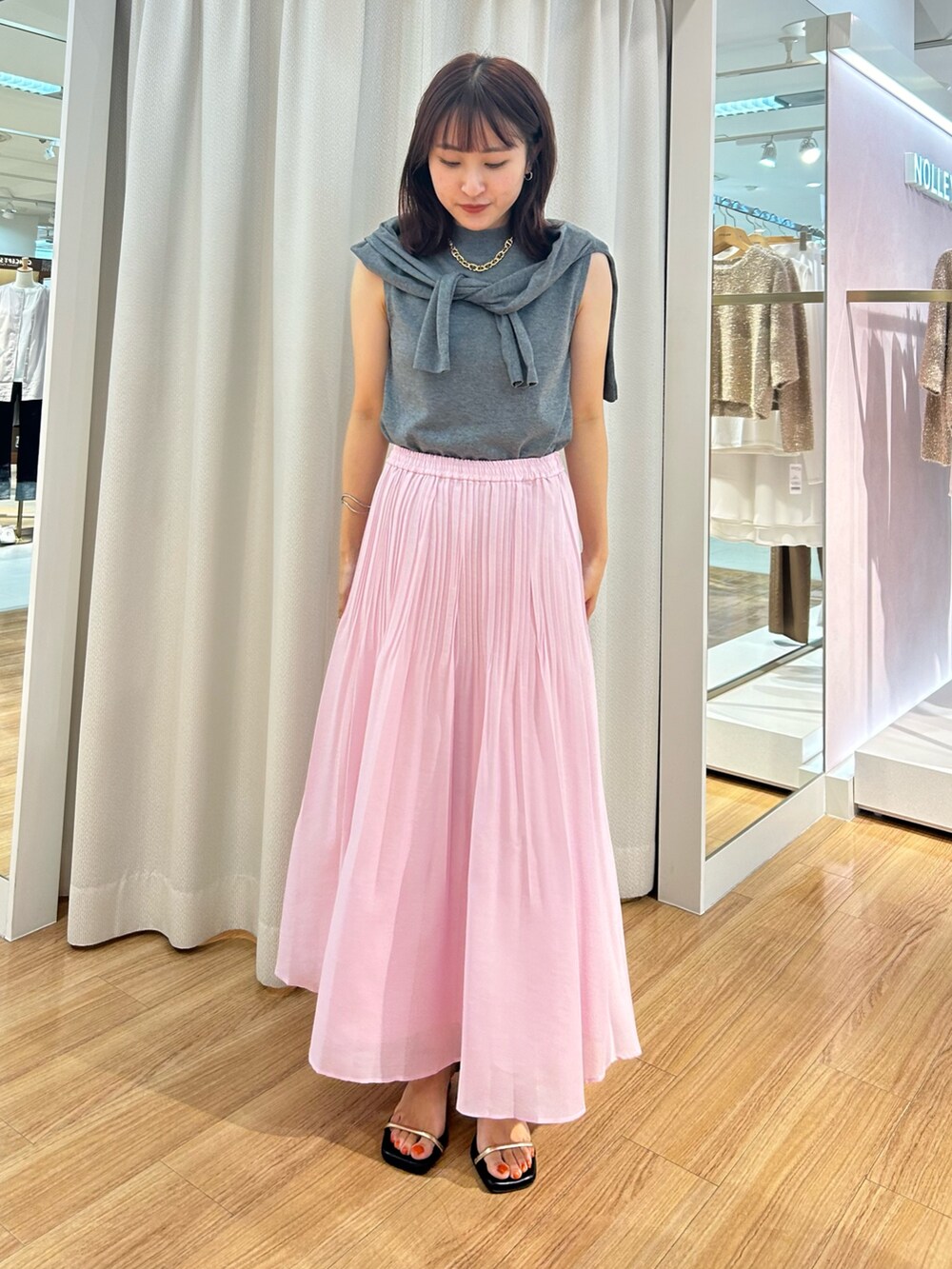 ピンク系のスカート、グレー系のカーディガン/ボレロ、グレー系のニット/セーターを着用したレディースの夏コーディネートの2枚目の写真