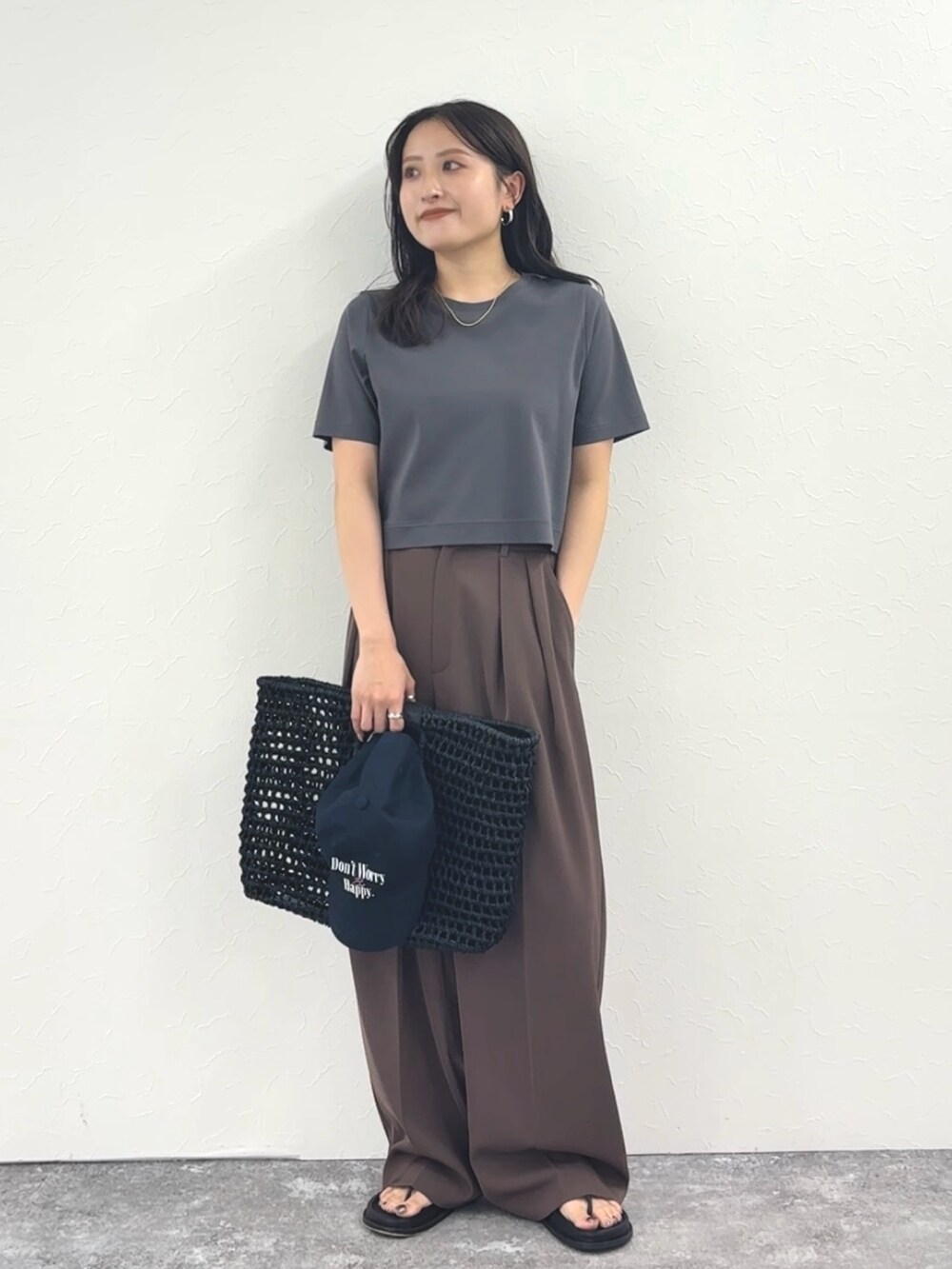 グレー系のTシャツ/カットソー、ブラウン系のその他パンツ、ブラック系のかごバッグを着用したレディースの春コーディネートの3枚目の写真