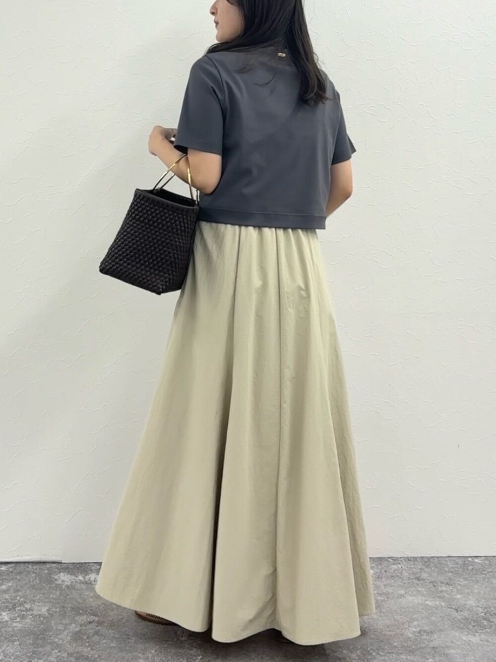 グレー系のTシャツ/カットソー、ベージュ系のスカート、ブラウン系のかごバッグを着用したレディースの春コーディネートの3枚目の写真
