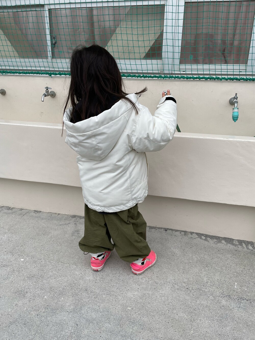 ホワイト系のブルゾン、グリーン系のその他パンツ、ピンク系のスニーカーを着用したキッズの冬コーディネートの2枚目の写真
