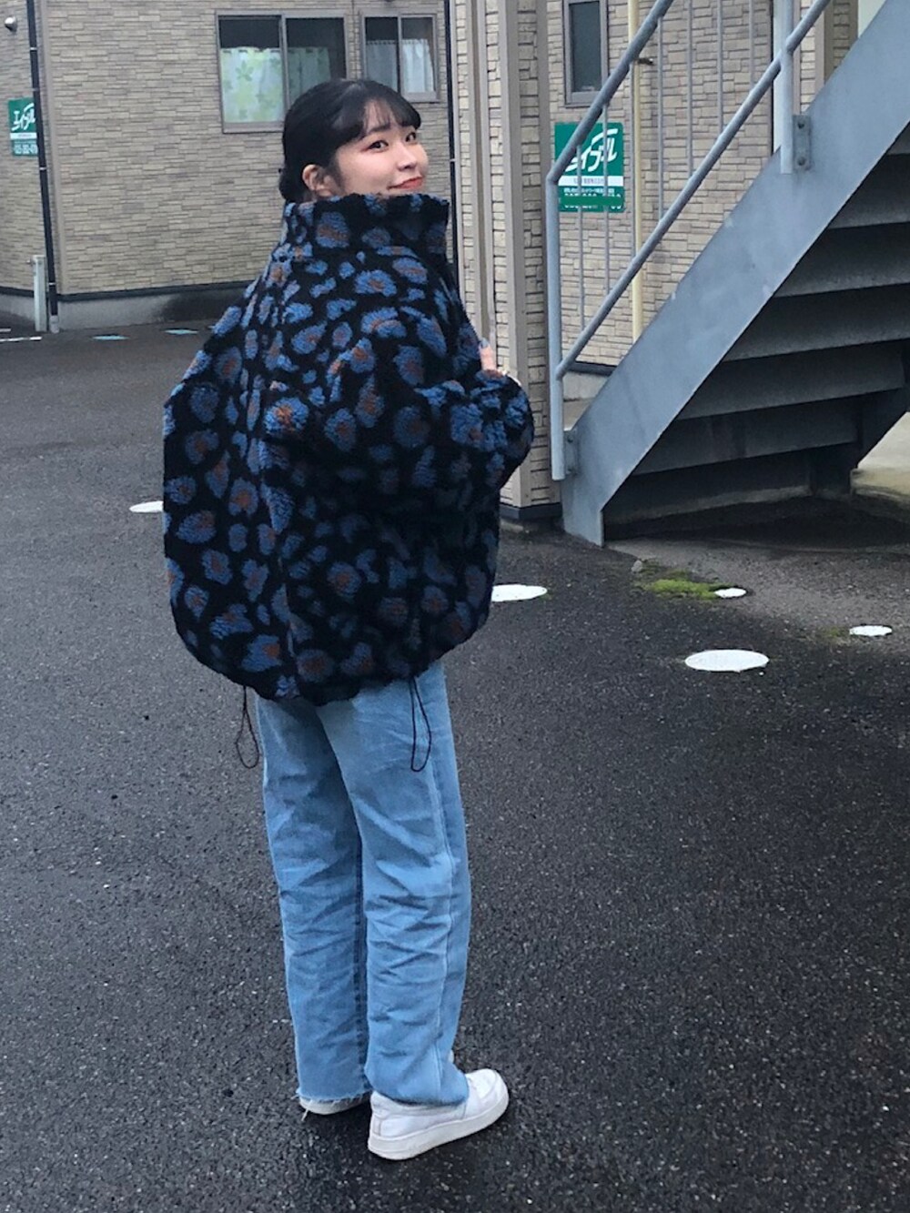 ブラック系のブルゾン、ブルー系のデニムパンツ、ホワイト系のスニーカーを着用したレディースの冬コーディネートの2枚目の写真