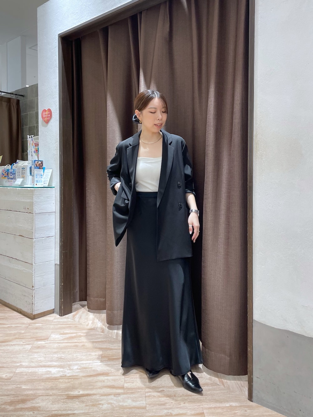 ブラック系のテーラードジャケット、ブラック系のスカート、ブラック系のパンプスを着用したレディースの秋コーディネートの2枚目の写真