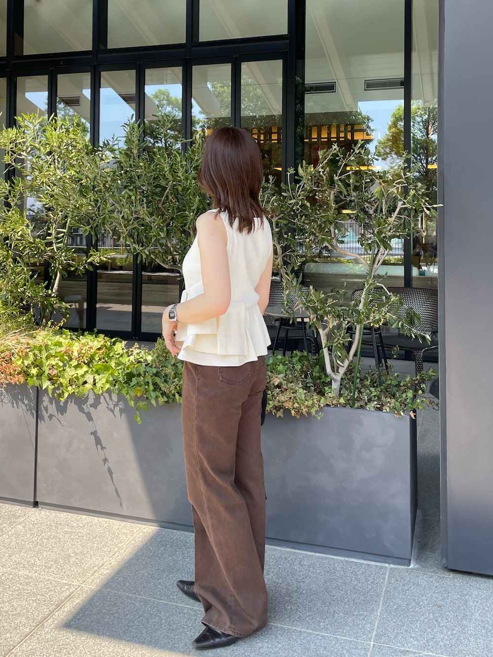 ホワイト系のニット/セーター、ブラウン系のデニムパンツを着用したレディースの夏コーディネートの2枚目の写真