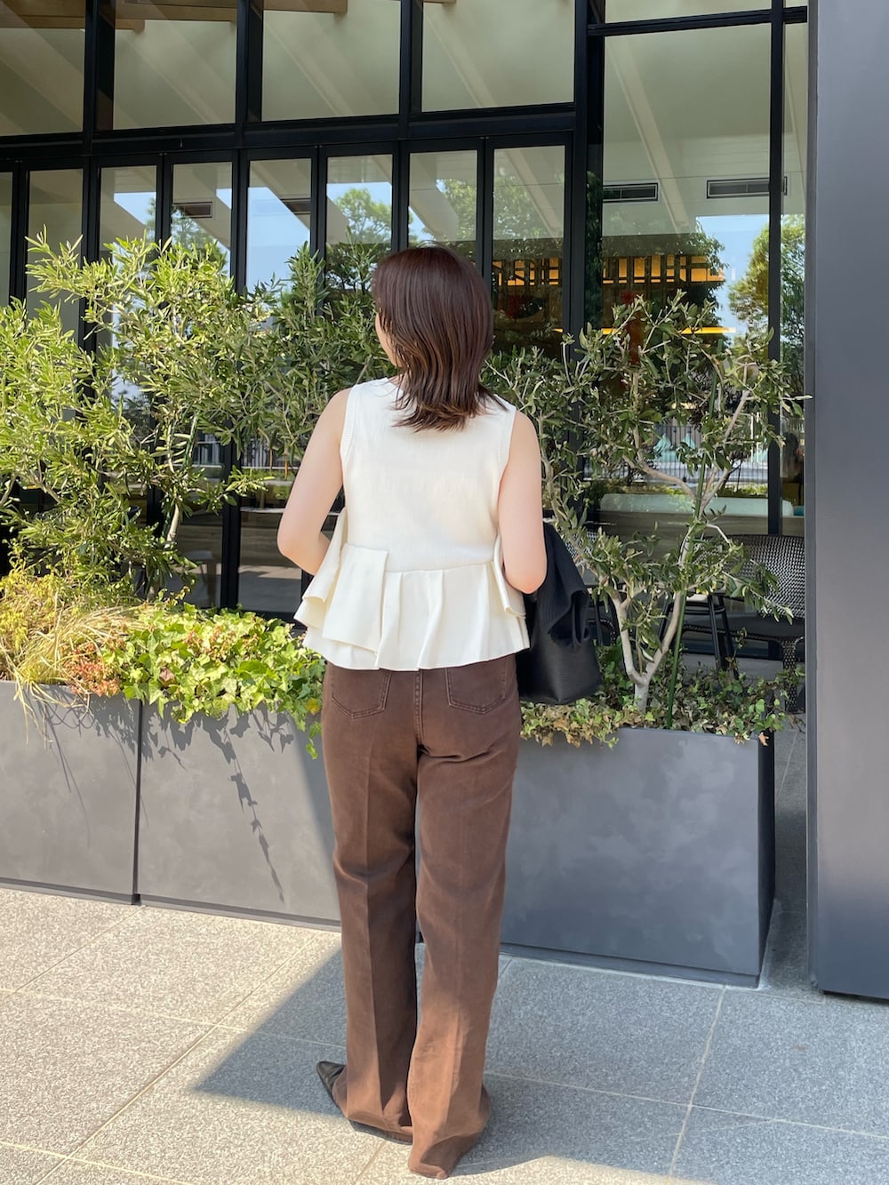 ホワイト系のニット/セーター、ブラウン系のデニムパンツを着用したレディースの夏コーディネートの4枚目の写真