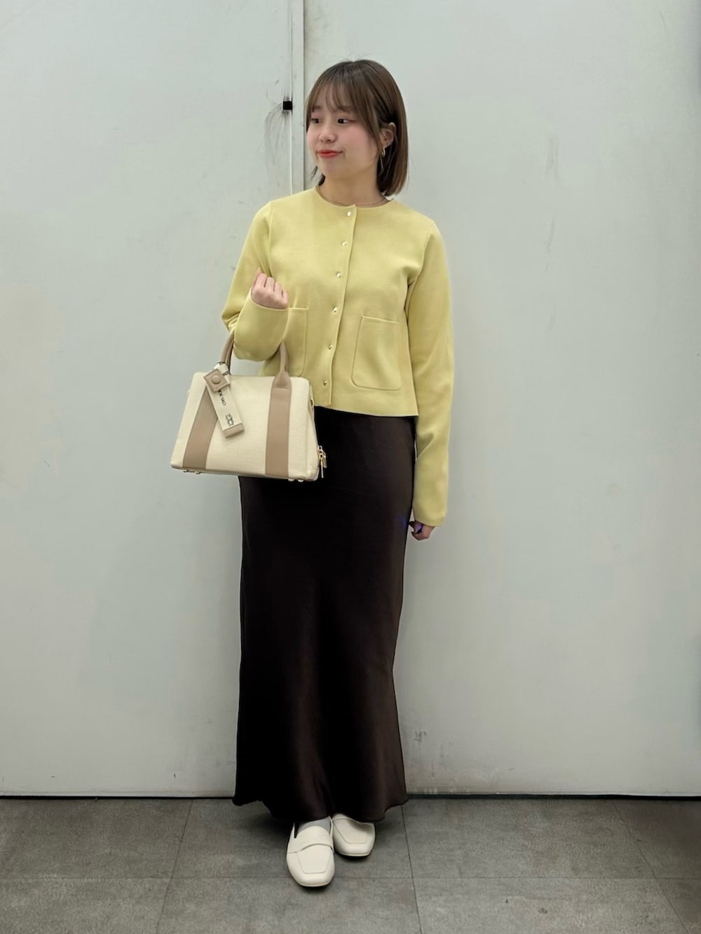 ベージュ系のニット/セーター、ブラウン系のスカート、ベージュ系のローファーを着用したレディースの春コーディネートの2枚目の写真