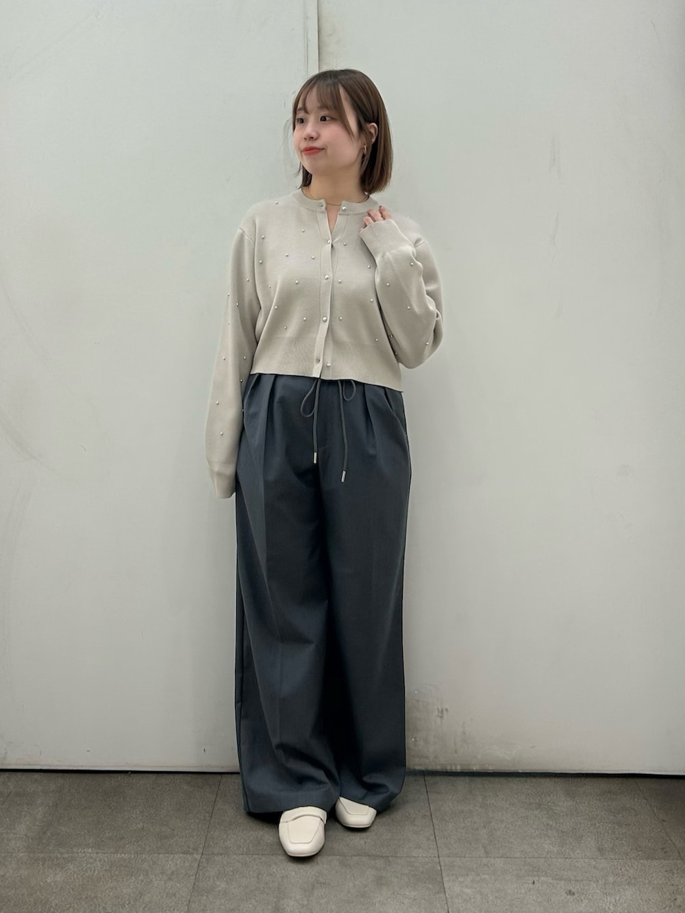 ベージュ系のカーディガン/ボレロ、グレー系のスラックス、ベージュ系のローファーを着用したレディースの春コーディネートの2枚目の写真