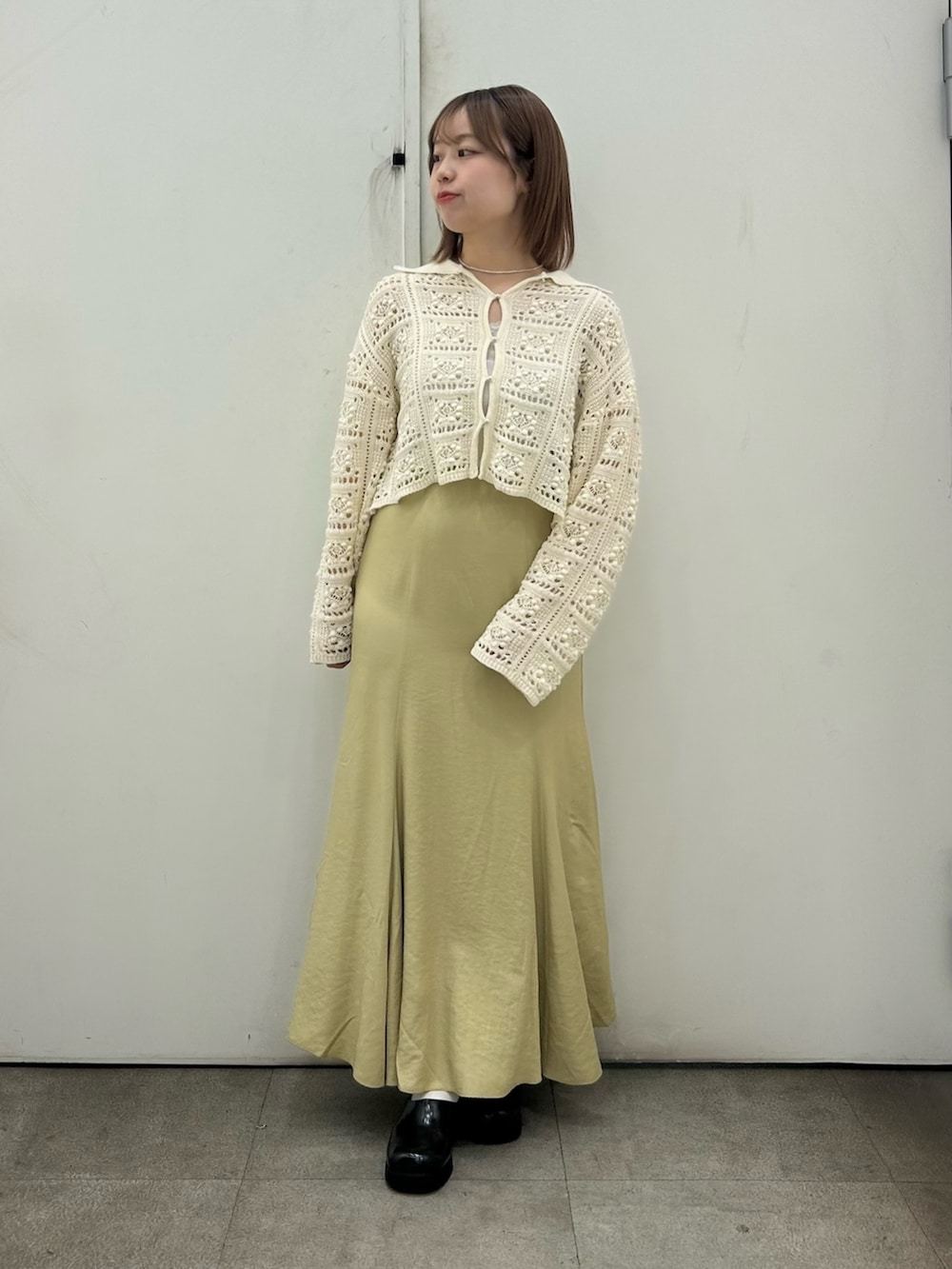 ホワイト系のカーディガン/ボレロ、ベージュ系のスカート、ブラック系のサンダルを着用したレディースの春コーディネートの2枚目の写真