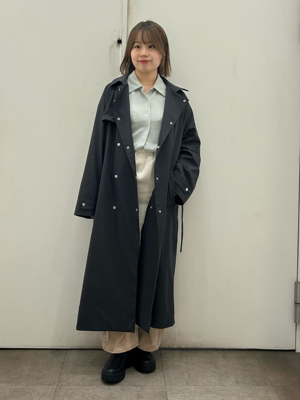 グレー系のトレンチコート、ベージュ系のデニムパンツ、グリーン系のシャツ/ブラウスを着用したレディースの冬コーディネートの2枚目の写真