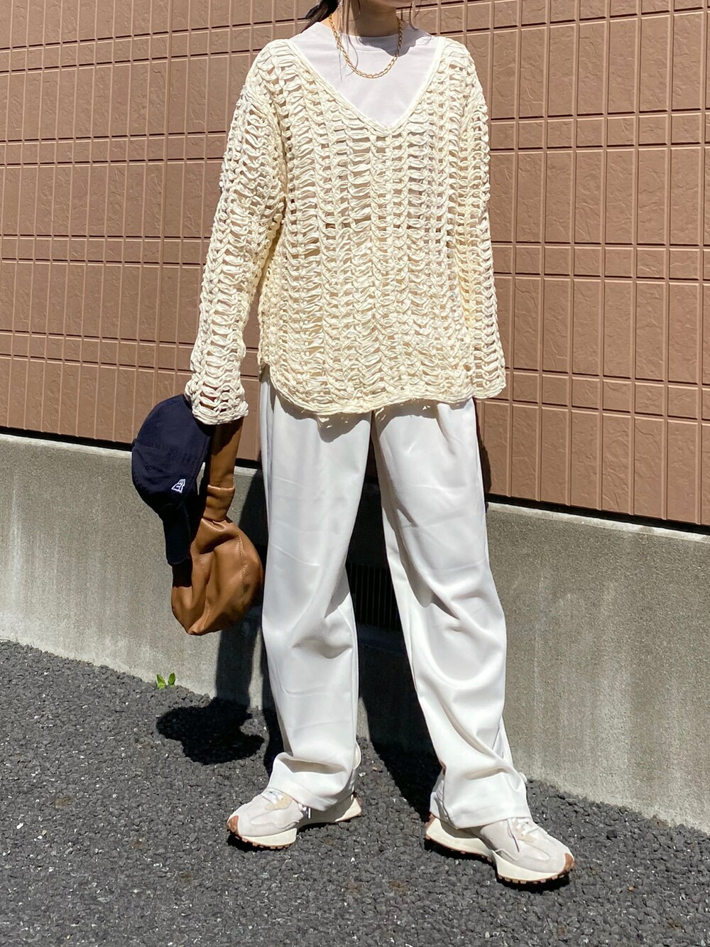 ホワイト系のニット/セーター、ブラウン系のバッグ、ホワイト系のスニーカーを着用したレディースの春コーディネートの2枚目の写真