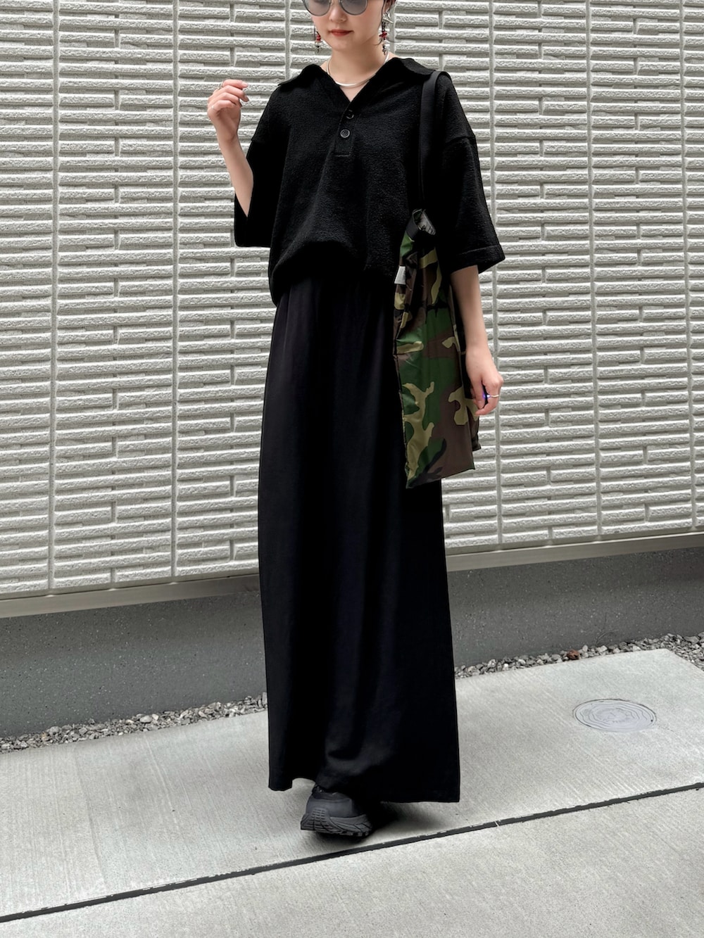 ブラック系のポロシャツ、ブラック系のスカート、グリーン系のトートバッグを着用したレディースの夏コーディネートの3枚目の写真