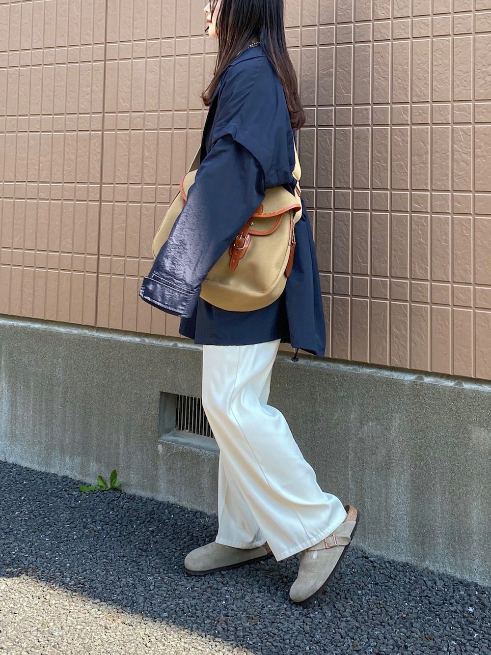 ブルー系のポンチョ、ブルー系のTシャツ/カットソー、ホワイト系のスラックスを着用したレディースの春コーディネートの3枚目の写真