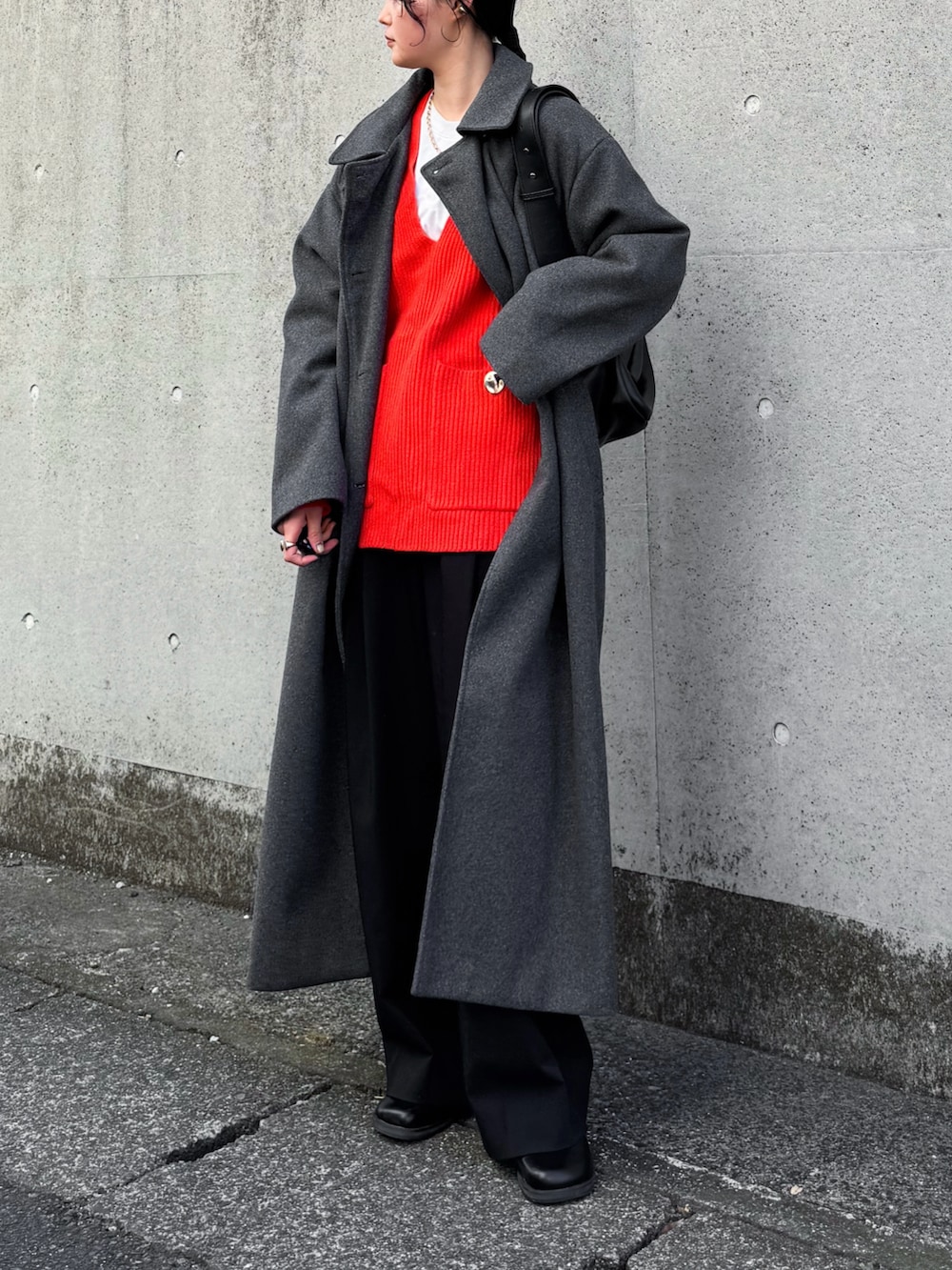 グレー系のステンカラーコート、レッド系のニット/セーター、ブラック系のその他パンツを着用したレディースの冬コーディネートの2枚目の写真