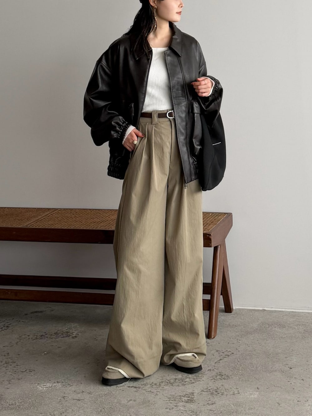 ベージュ系のスラックス、ホワイト系のニット/セーター、ブラウン系のブルゾンを着用したレディースの冬コーディネートの2枚目の写真