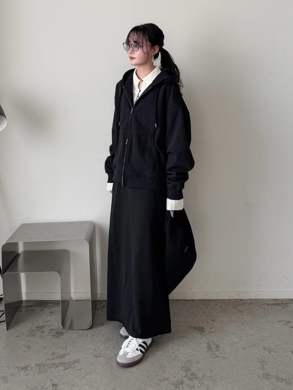 ブラック系のパーカー、ホワイト系のニット/セーター、ブラック系のスカートを着用したレディースの冬コーディネートの3枚目の写真