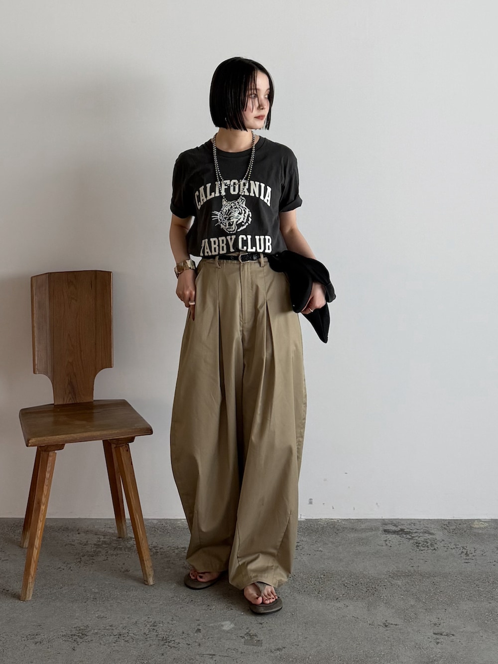 ブラック系のTシャツ/カットソー、ベージュ系のチノパンツ、ベージュ系のサンダルを着用したレディースの夏コーディネートの2枚目の写真