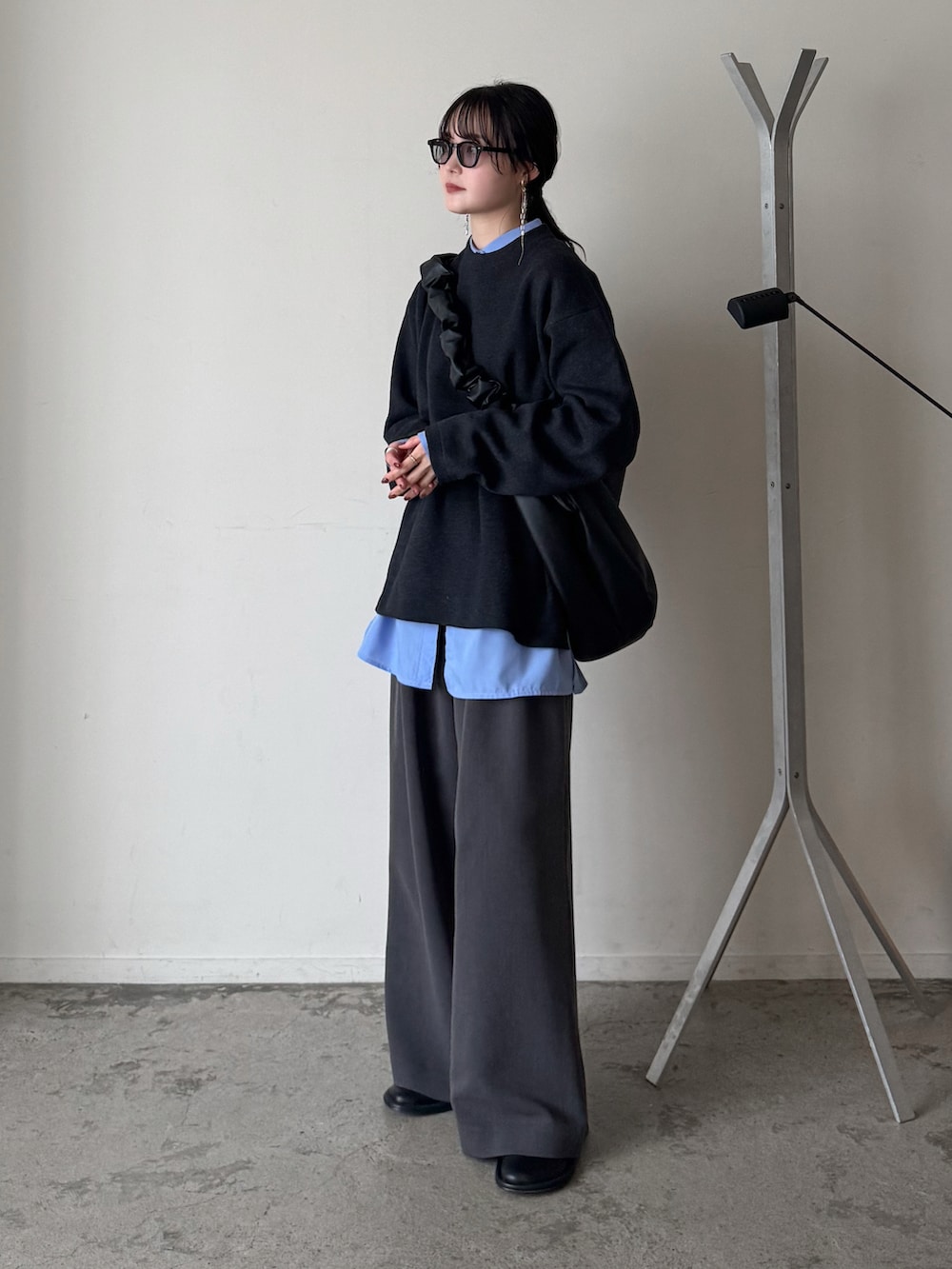 グレー系のニット/セーター、ブルー系のシャツ/ブラウス、グレー系のスラックスを着用したレディースの春コーディネートの2枚目の写真