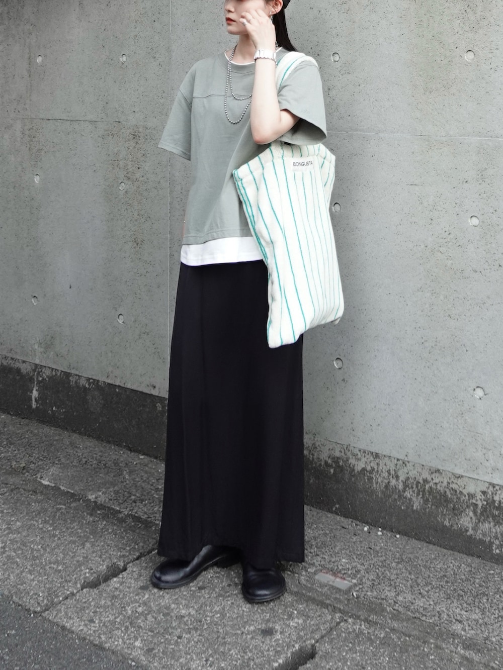 ブラック系のスカート、ホワイト系のトートバッグ、グリーン系のTシャツ/カットソーを着用したレディースの夏コーディネートの2枚目の写真