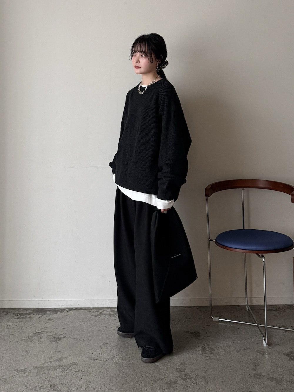 グレー系のニット/セーター、ホワイト系のTシャツ/カットソー、ブラック系のスラックスを着用したレディースの春コーディネートの2枚目の写真