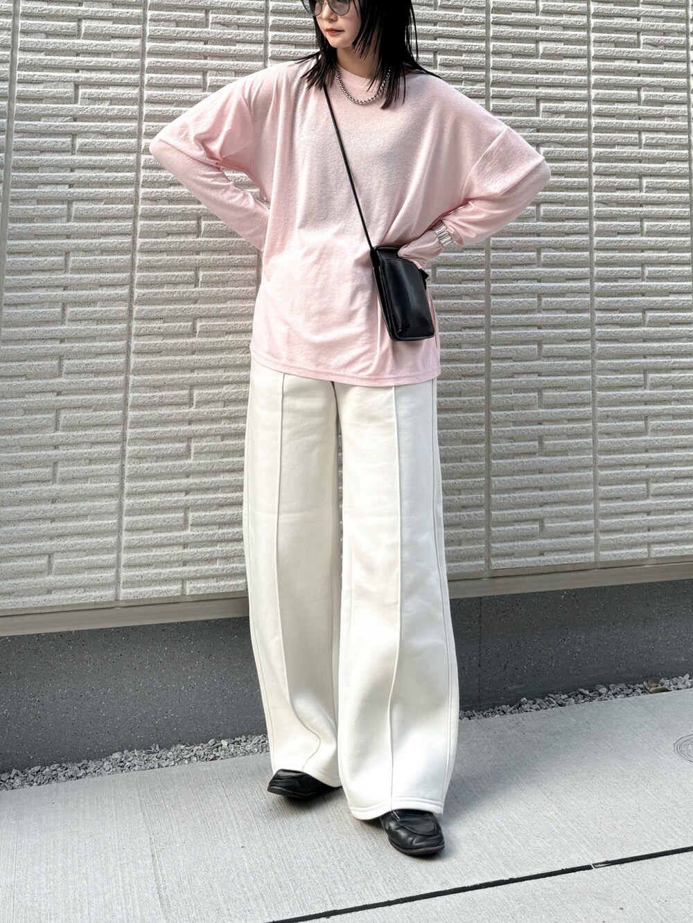 ピンク系のTシャツ/カットソー、ホワイト系のパンツ、ブラック系のショルダーバッグを着用したレディースの春コーディネートの2枚目の写真