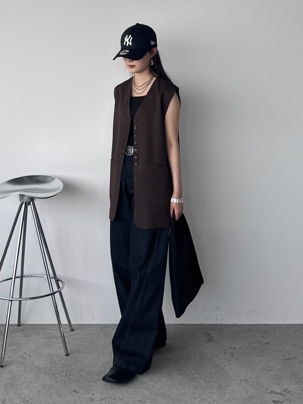 ブラウン系のベスト、ブルー系のデニムパンツ、ブラック系のハンドバッグを着用したレディースの夏コーディネートの2枚目の写真