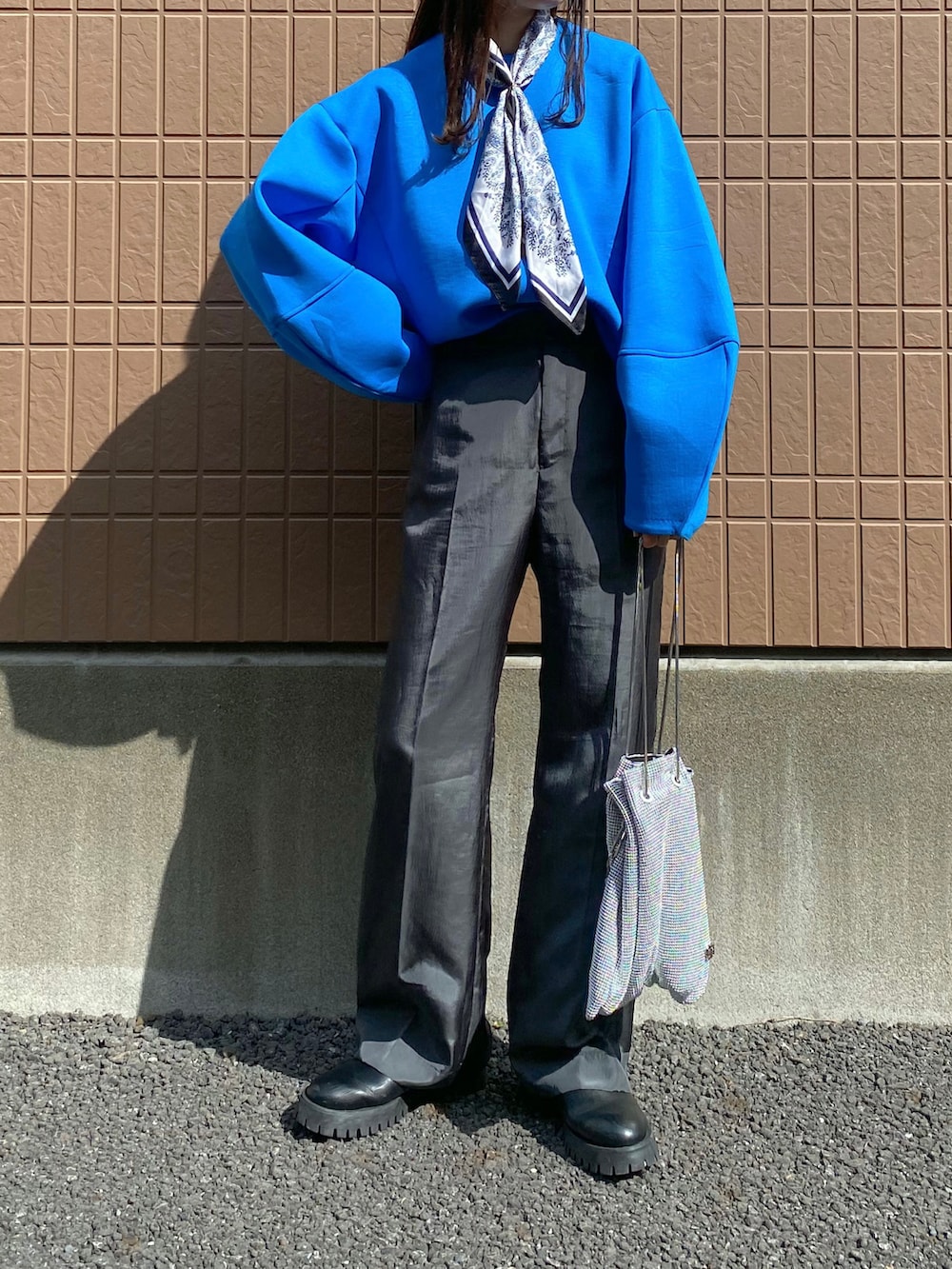 ブルー系のニット/セーター、グレー系のその他パンツ、シルバー系のショルダーバッグを着用したレディースの春コーディネートの2枚目の写真