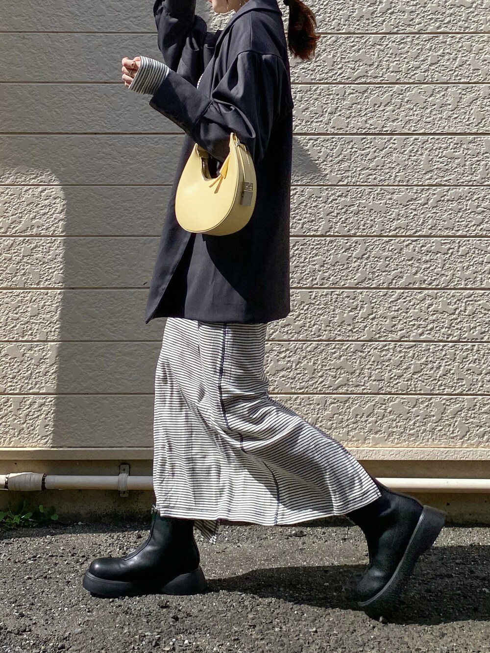 グレー系のテーラードジャケット、ブルー系のワンピース、イエロー系のハンドバッグを着用したレディースの秋コーディネートの2枚目の写真