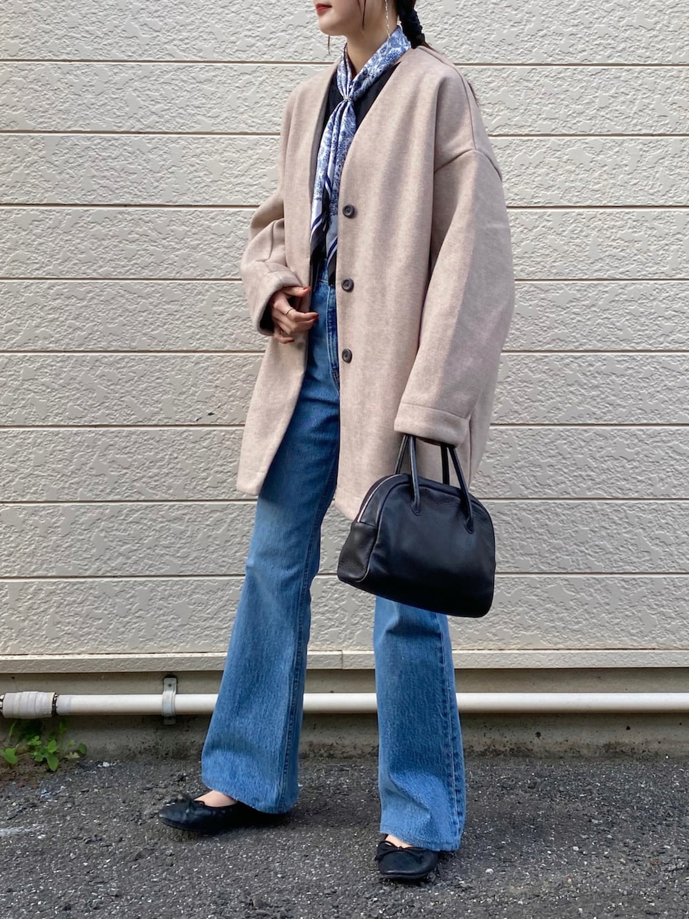 ピンク系のノーカラーコート、ブルー系のデニムパンツ、ブラック系のショルダーバッグを着用したレディースの冬コーディネートの2枚目の写真