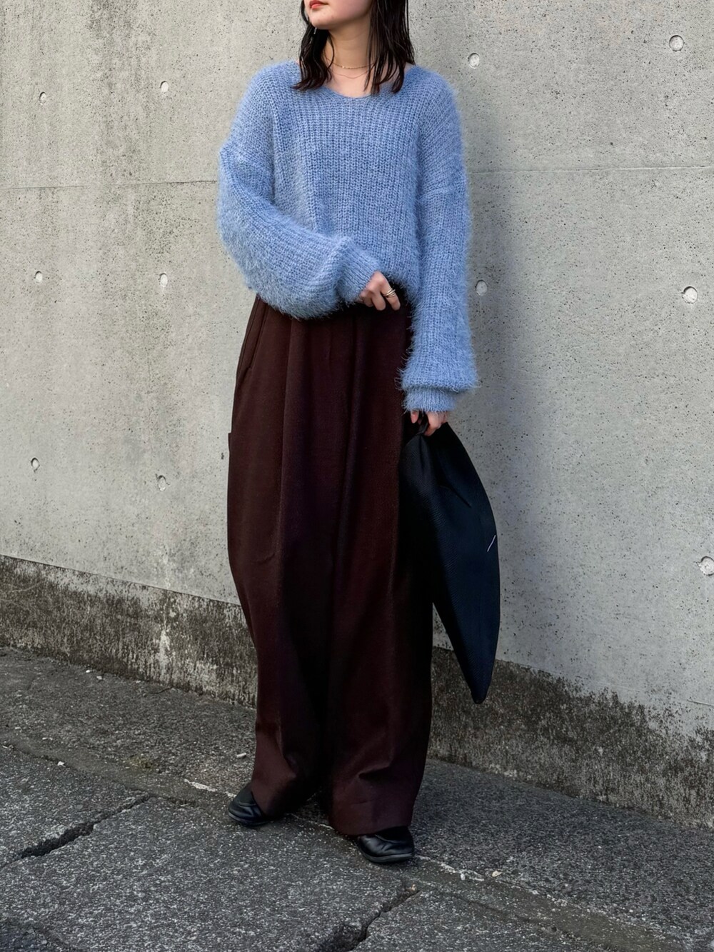 ブルー系のニット/セーター、ブラウン系のその他パンツ、ブラック系のトートバッグを着用したレディースの冬コーディネートの3枚目の写真