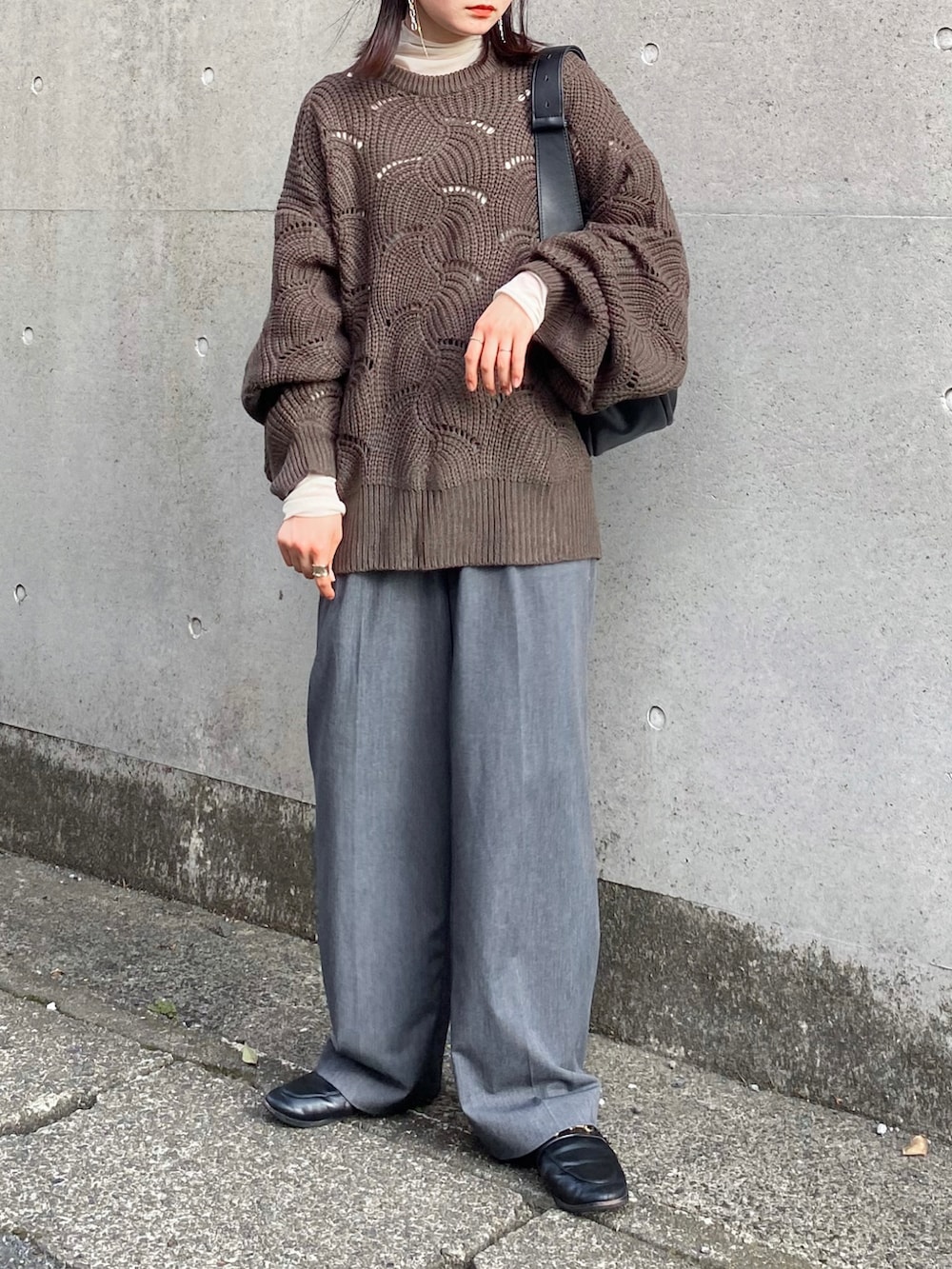 グリーン系のニット/セーター、グレー系のスラックス、ブラック系のショルダーバッグを着用したレディースの秋コーディネートの3枚目の写真