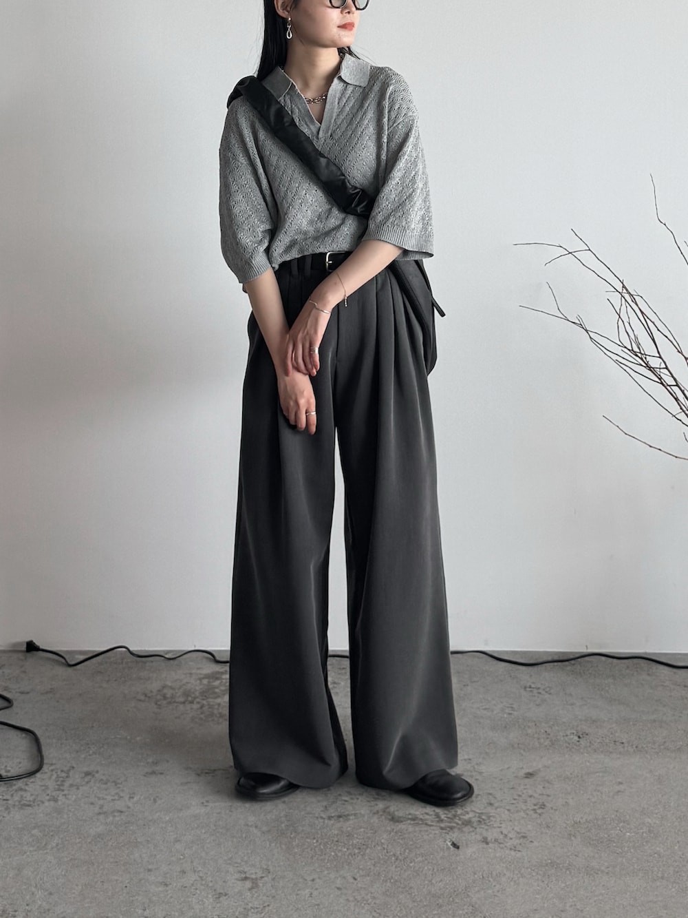 グレー系のポロシャツ、グレー系のスラックス、ブラック系のショルダーバッグを着用したレディースの夏コーディネートの2枚目の写真