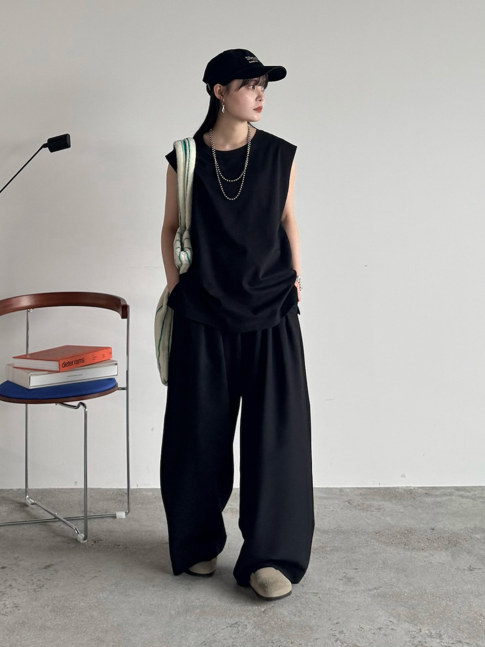 ブラック系のタンクトップ、ブラック系のスラックス、ホワイト系のトートバッグを着用したレディースの夏コーディネートの2枚目の写真