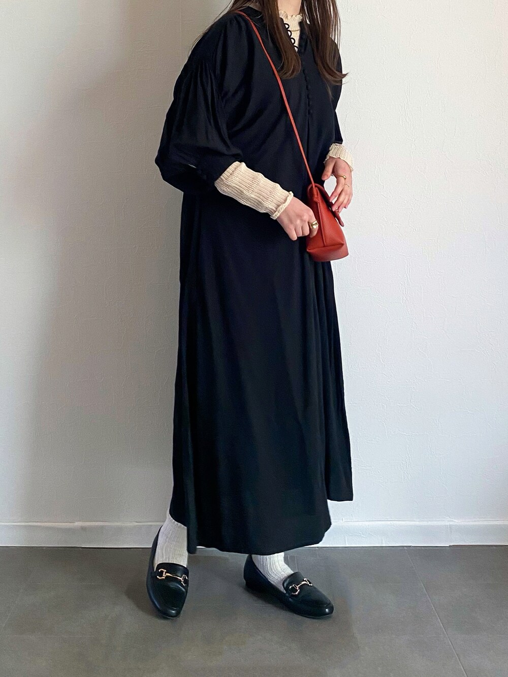 ブラック系のワンピース、ホワイト系のニット/セーター、オレンジ系のショルダーバッグを着用したレディースの春コーディネートの2枚目の写真