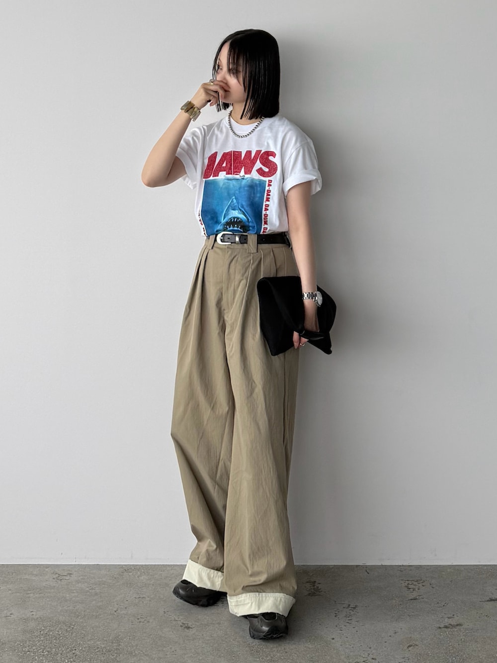 ベージュ系のスラックス、ホワイト系のTシャツ/カットソー、ブラック系のスニーカーを着用したレディースの夏コーディネートの2枚目の写真