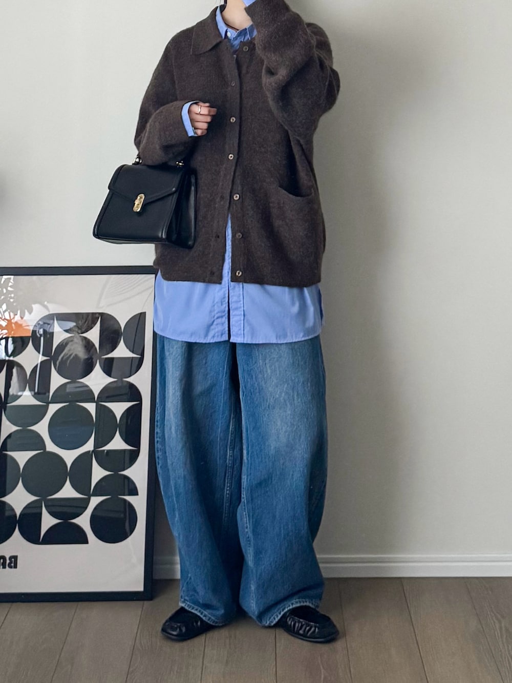 ブラック系のトートバッグ、ブラウン系のニット/セーター、ブルー系のシャツ/ブラウスを着用したレディースの秋コーディネートの2枚目の写真