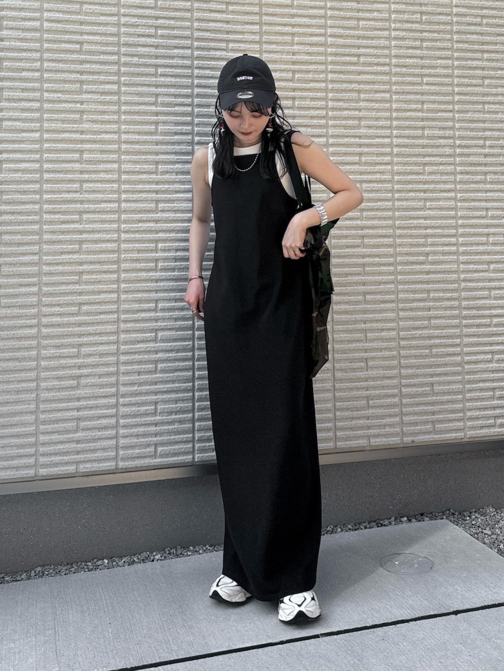 ブラック系のワンピース、グリーン系のトートバッグ、ホワイト系のスニーカーを着用したレディースの夏コーディネートの2枚目の写真