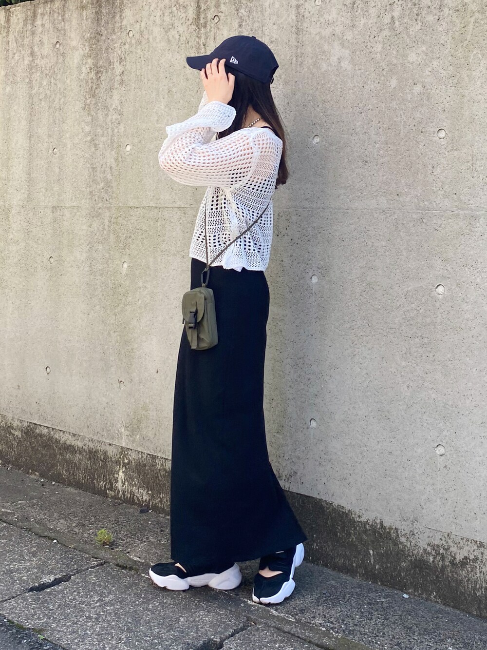 ホワイト系のニット/セーター、ブラック系のワンピース、グリーン系のショルダーバッグを着用したレディースの春コーディネートの2枚目の写真