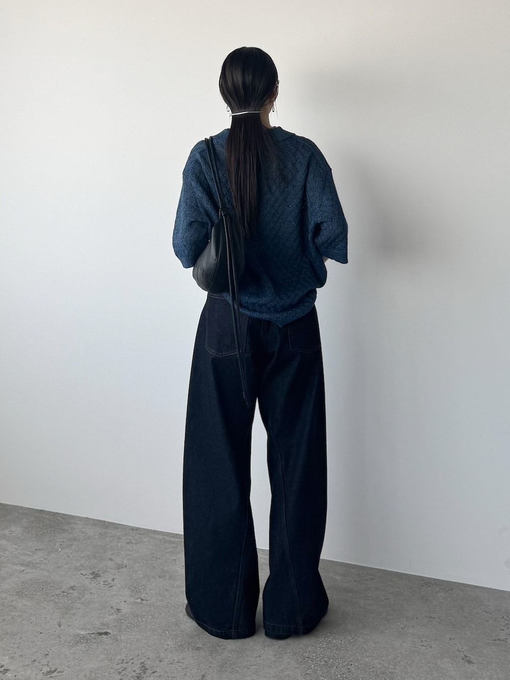 ブルー系のポロシャツ、ブルー系のデニムパンツ、ブラック系のショルダーバッグを着用したレディースの夏コーディネートの3枚目の写真