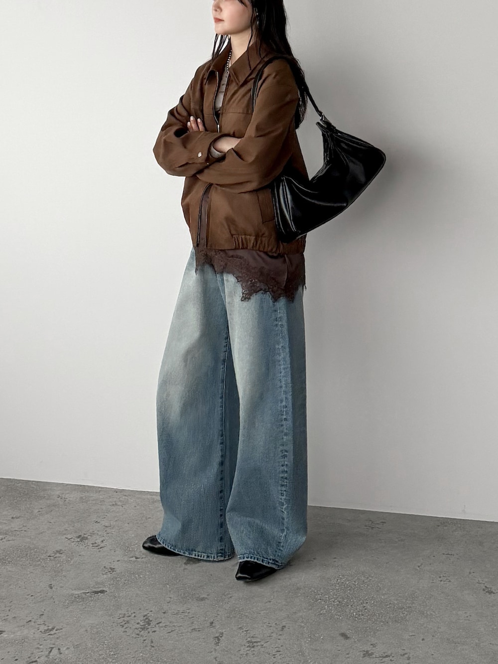 ブラウン系のキャミソール、ブラウン系のブルゾン、ブルー系のデニムパンツを着用したレディースの春コーディネートの2枚目の写真