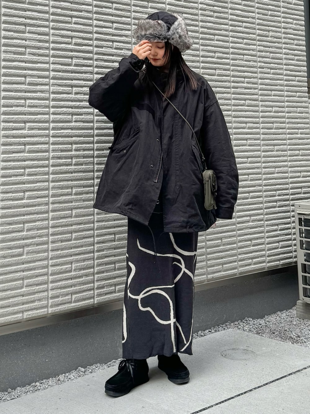 ブラック系のモッズコート、グレー系のスカート、グリーン系のショルダーバッグを着用したレディースの冬コーディネートの2枚目の写真