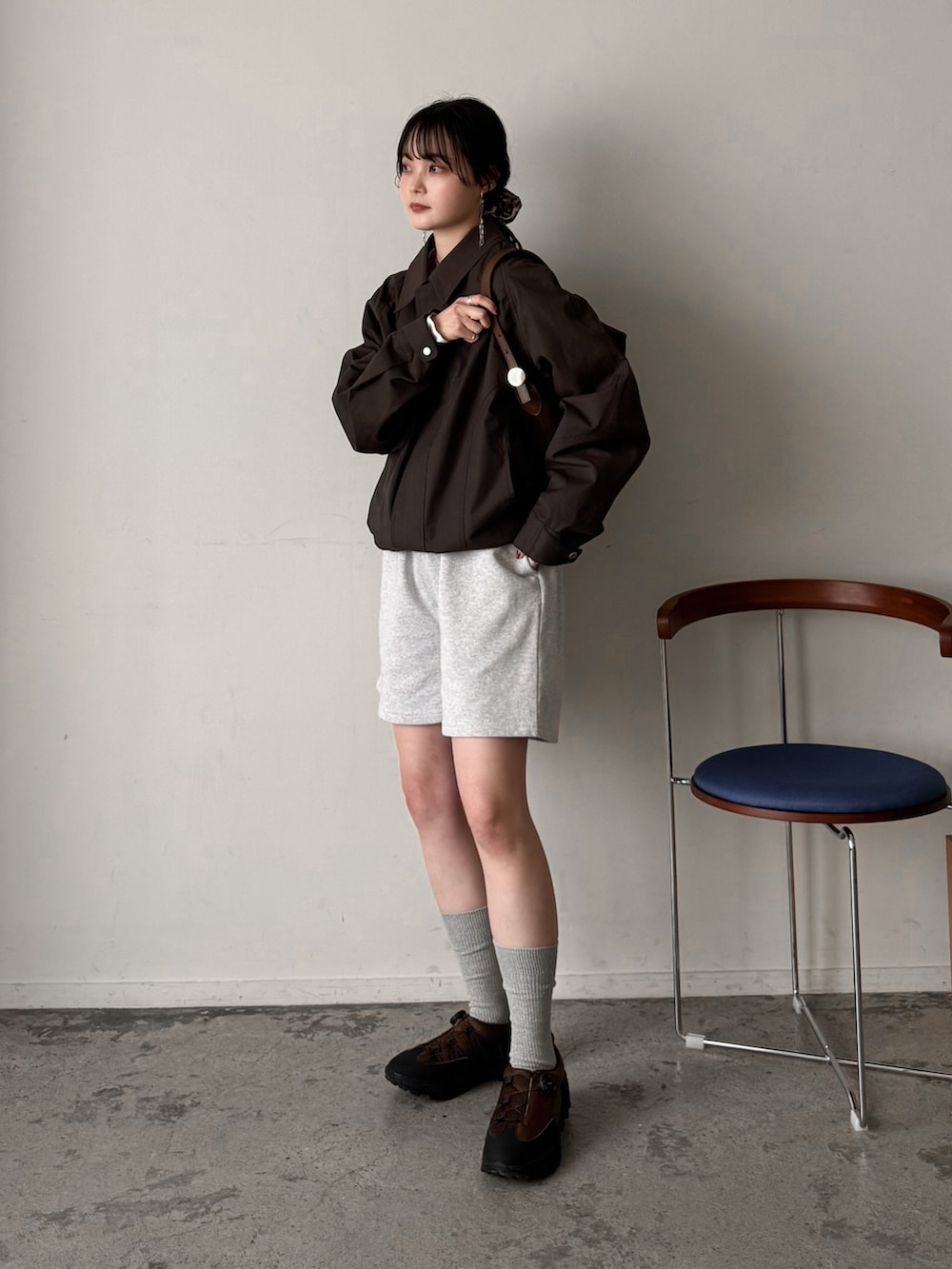 ブラウン系のブルゾン、グレー系のその他パンツ、ブラウン系のショルダーバッグを着用したレディースの春コーディネートの2枚目の写真