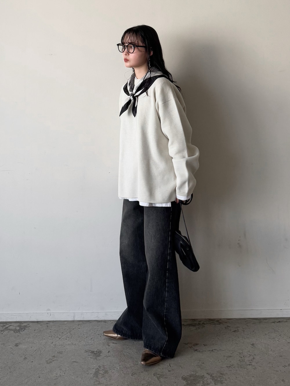 ホワイト系のニット/セーター、ブラック系のデニムパンツ、ゴールド系のパンプスを着用したレディースの冬コーディネートの2枚目の写真