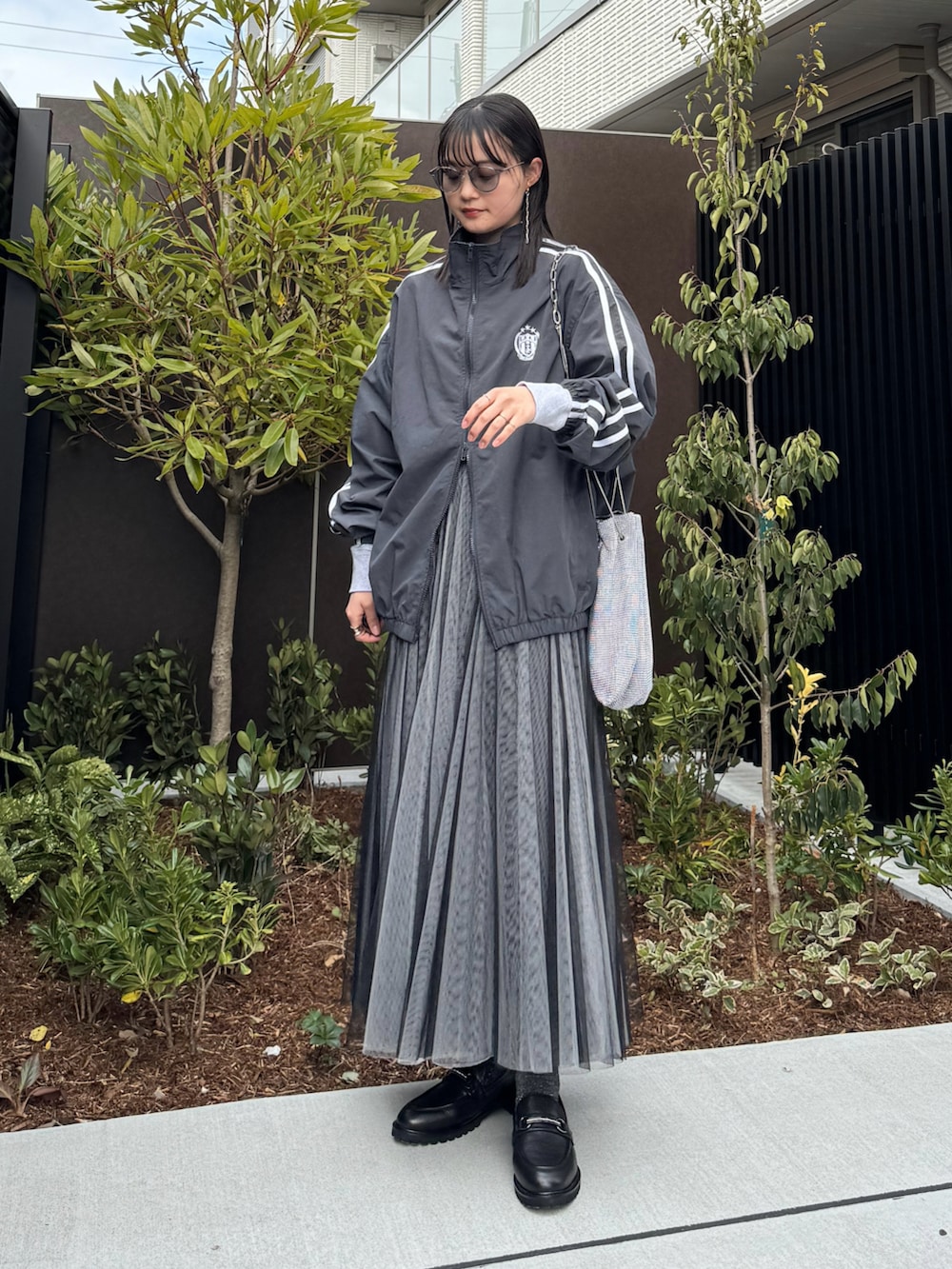 ブラック系のローファー、グレー系のナイロンジャケット、ブラック系のスカートを着用したレディースの冬コーディネートの3枚目の写真