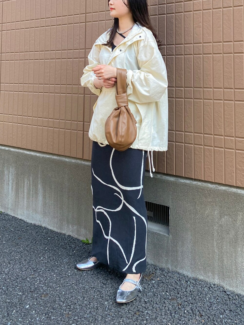 ホワイト系のマウンテンパーカー、ブラック系のタンクトップ、グレー系のスカートを着用したレディースの春コーディネートの2枚目の写真