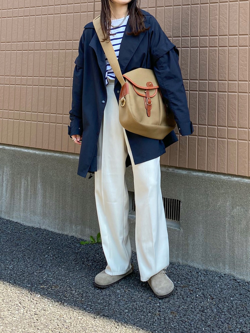 ブルー系のポンチョ、ブルー系のTシャツ/カットソー、ホワイト系のスラックスを着用したレディースの春コーディネートの2枚目の写真